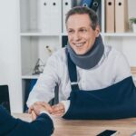 worker-in-neck-brace-with-brokenarm-and-businessma-7JZ5EFY-1