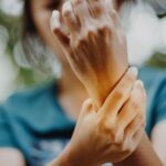 Woman holding her wrist in pain with blurred background_s