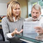 A woman in a wheelchair with a man going over paperwork_s