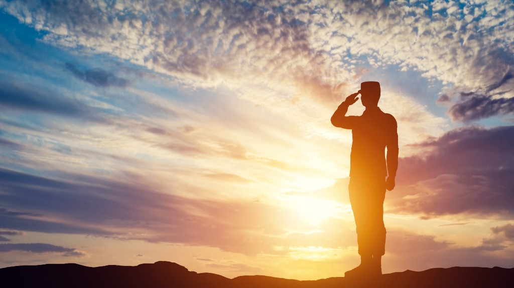 Soldier saluting in front of setting sun