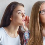 Woman saying something in another woman’s ear_s
