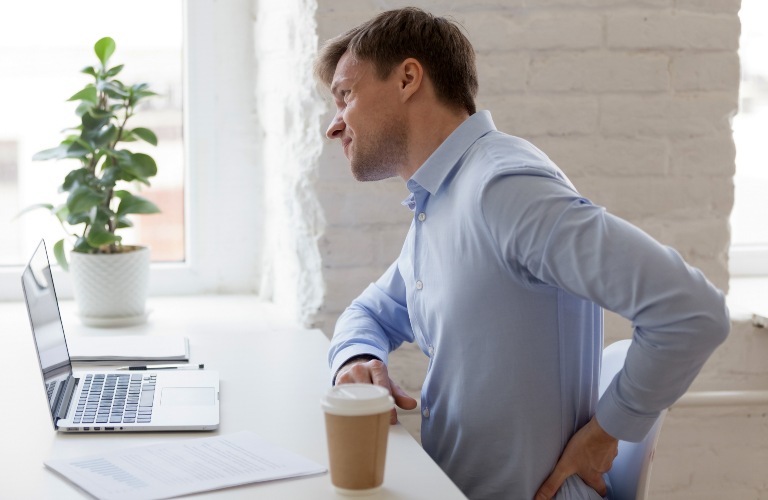 Man with hurt back at desk