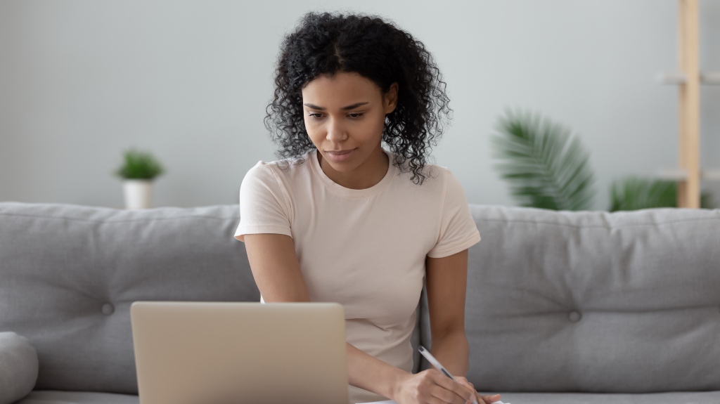 Woman looking at a computer and taking notes