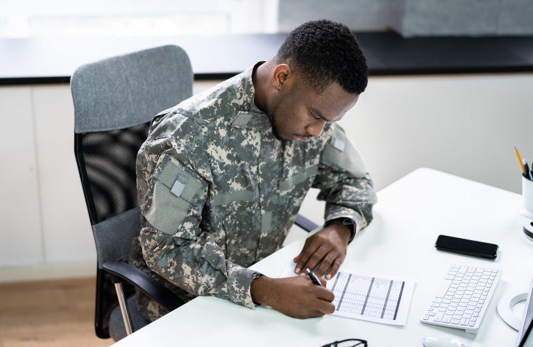 Military man filling out paperwork in front of a computer