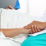 doctor holding patient’s hand in bed_s