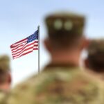 military personnel out of focus with flag in background_s