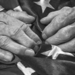 elderly hands on an American flag in black and white_s