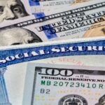 Closeup of Social Security benefits identification card with 100 dollar bills