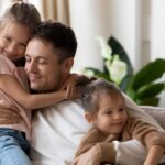 Pleased dad sit on couch with kids_s