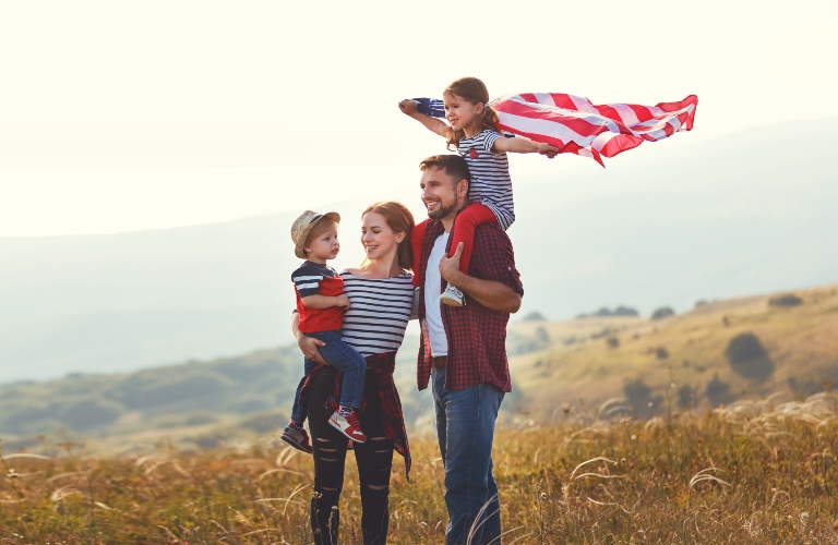 happy family with the flag of america USA at sunset outdoors