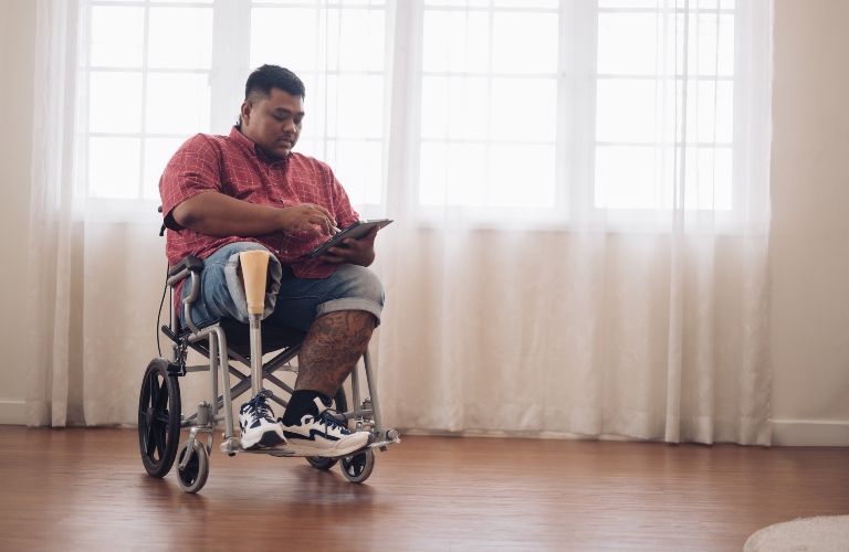 man sits on a wheelchair and uses a tablet