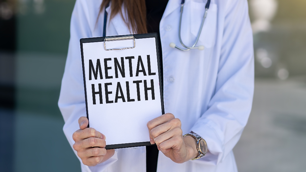 Doctor holding clipboard with Mental Health text on a sheet of paper
