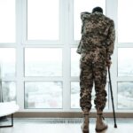 A disabled soldier stands with his hand on the window_s