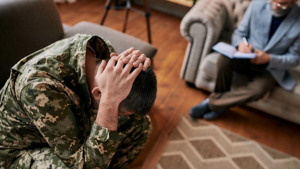 Middle aged military man holding his head