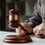 Hand of soldier holding judge’s gavel_s