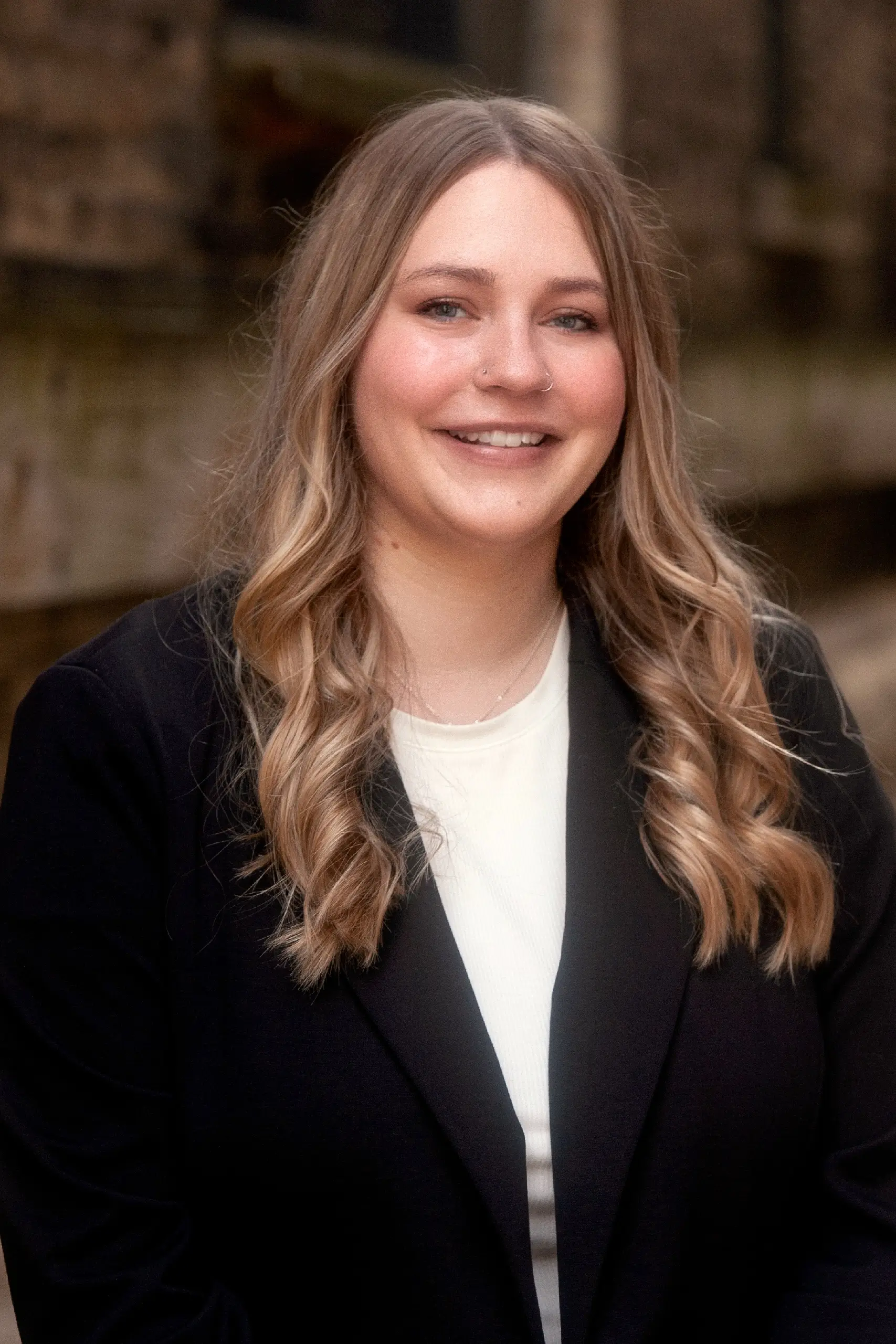 Professional portrait of a smiling woman with long blonde hair, black blazer, and white top.