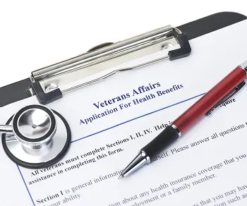Application form titled "Veterans Affairs Application for Health Benefits" with a stethoscope and red pen on a clipboard.