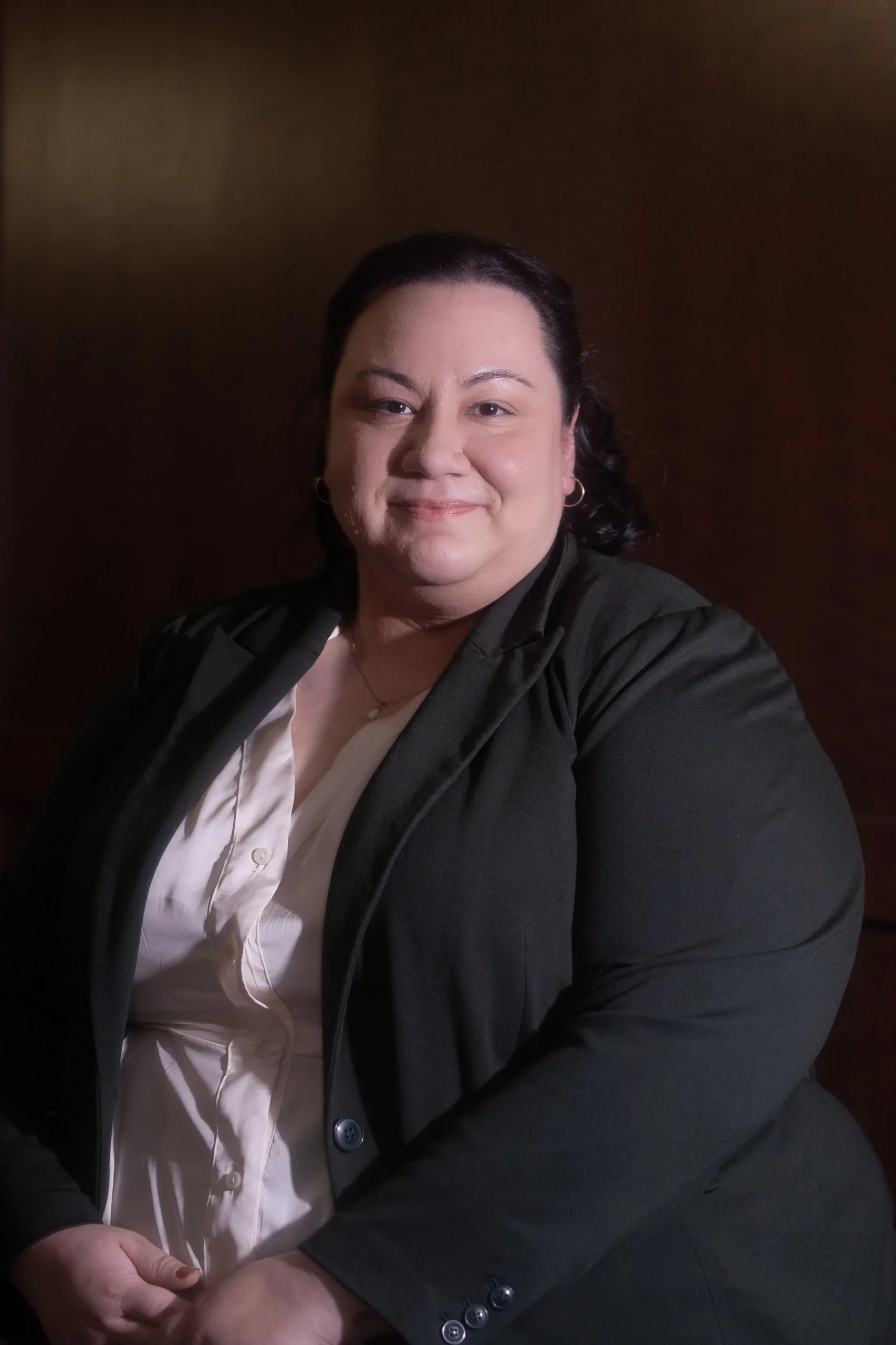Professional portrait of a woman with dark hair wearing a black blazer and white blouse.