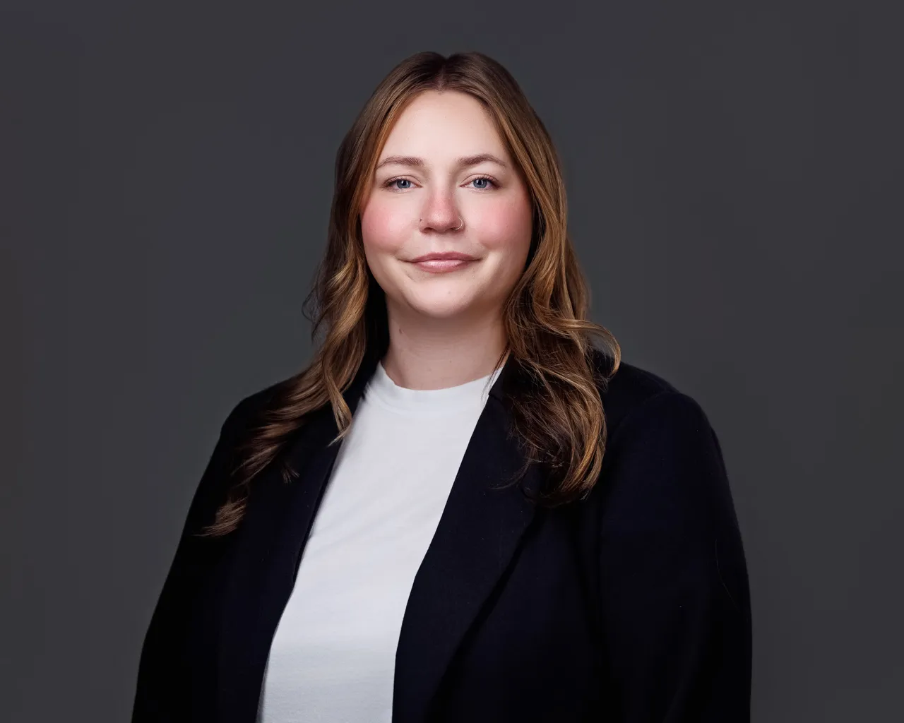 Professional portrait of a woman with light brown hair, wearing a black blazer and white shirt.