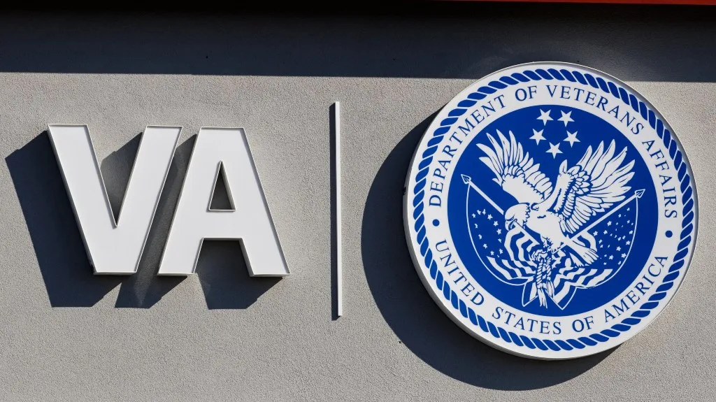 Signage on a gray wall displaying "VA" and the Department of Veterans Affairs blue and white seal.