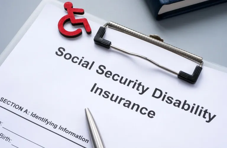 Social Security Disability Insurance application form on clipboard with pen and red disability symbol.