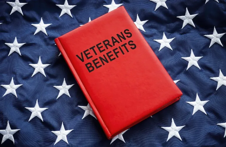 Red book titled "Veterans Benefits" placed on a folded American flag with white stars.