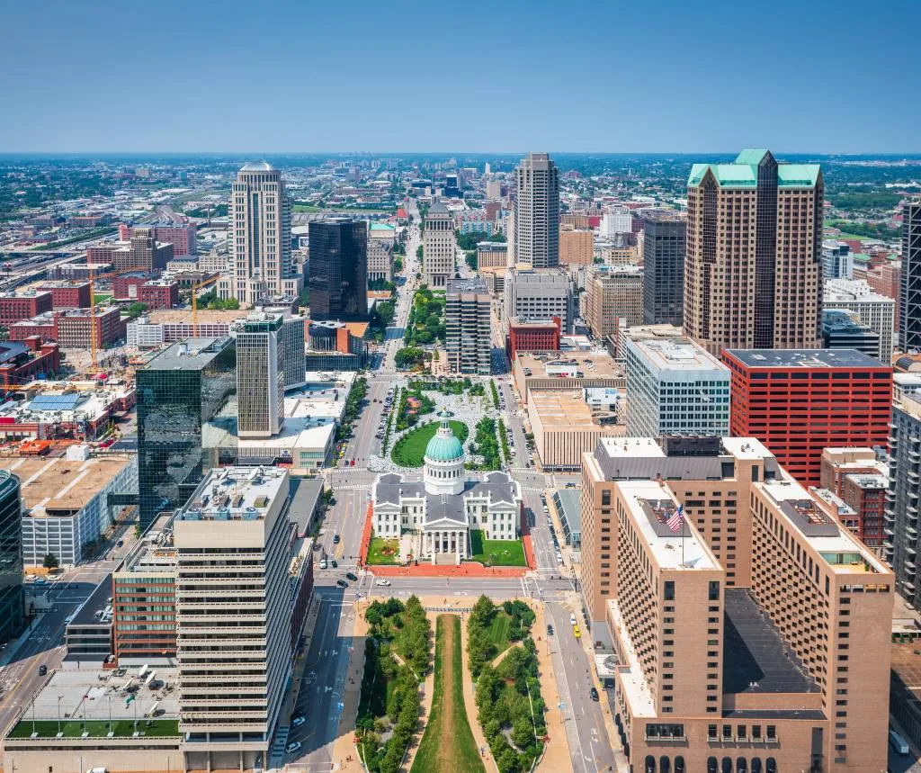 Aerial view of downtown cityscape with modern skyscrapers and a historic courthouse with a green dome.